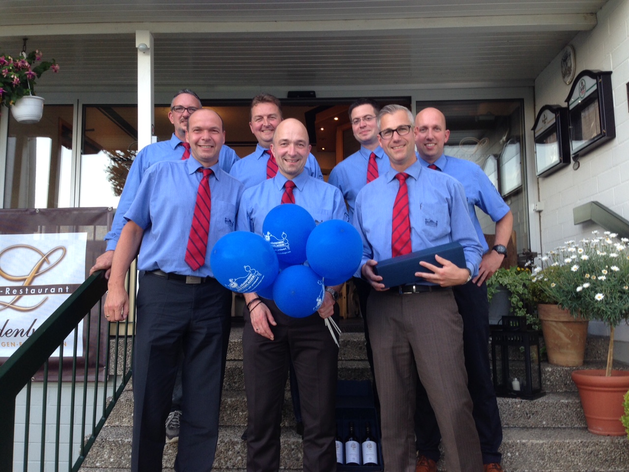 Un groupe d'hommes debout ensemble souriant portant une chemise bleue et une cravate