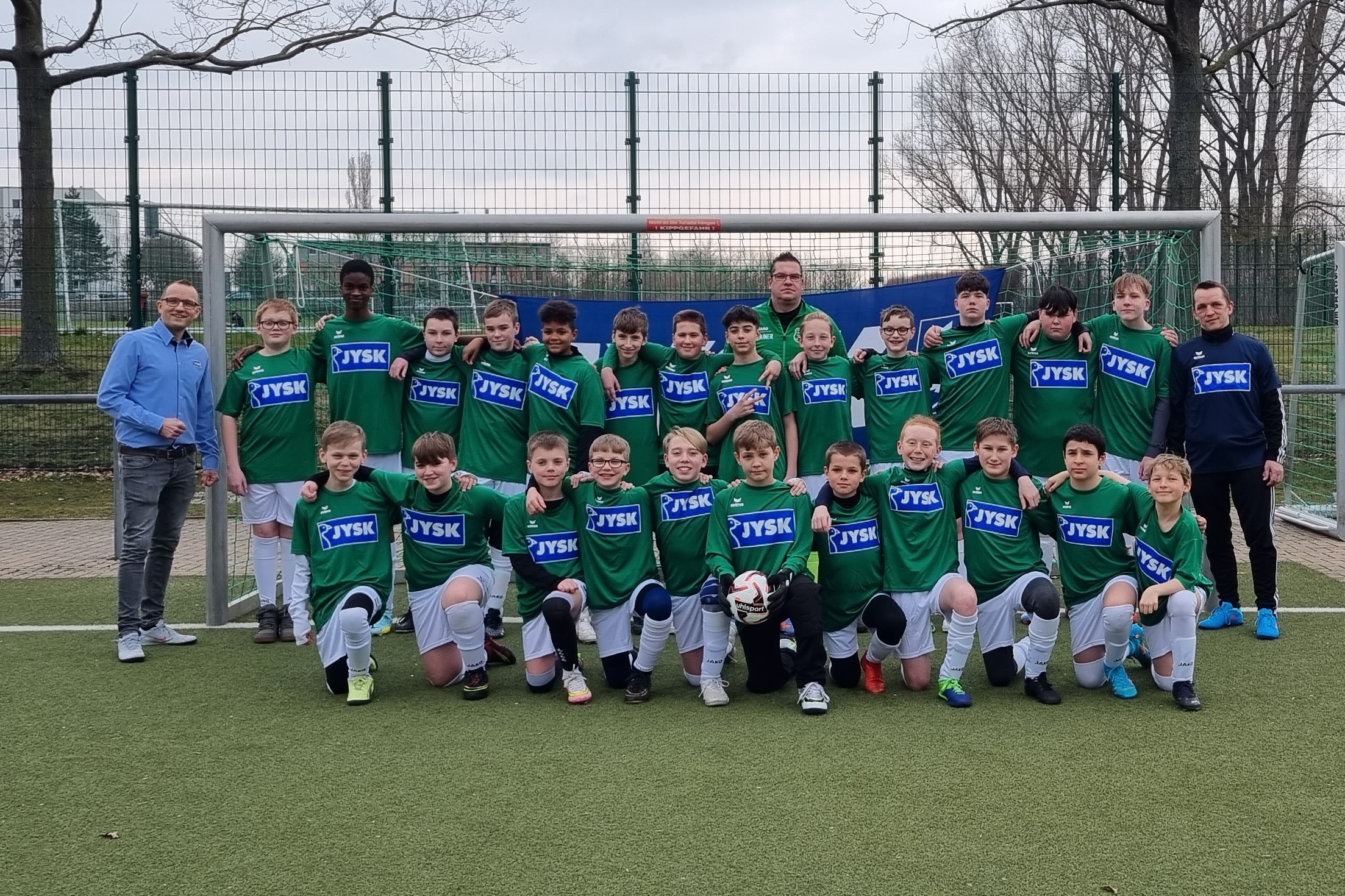 Mehere Jungen in JYSK-Trikots stehen vor einem Fußballtor