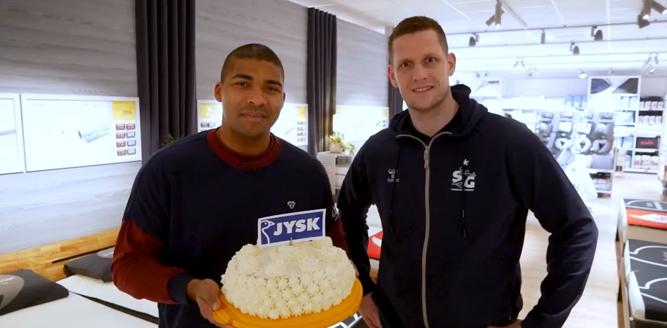 Zwei Männer mit Torte in der Hand stehen im Matratzenstudio 