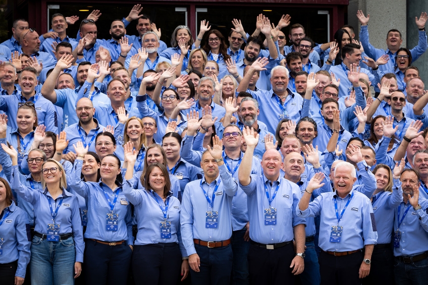 Eine Gruppe von JYSK-Einzelhandelskollegen in blauen Hemden winkt