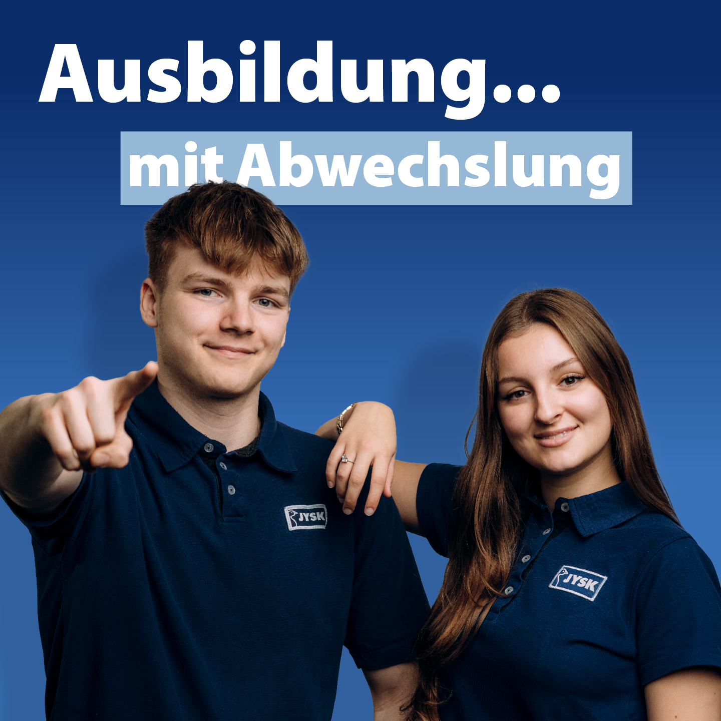 Ein junger Mann und eine junge Frau lächeln in die Kamera. Beide tragen JYSK-Poloshirts. Die Frau stützt ihren Arm lässig auf der Schulter des Mannes ab.
