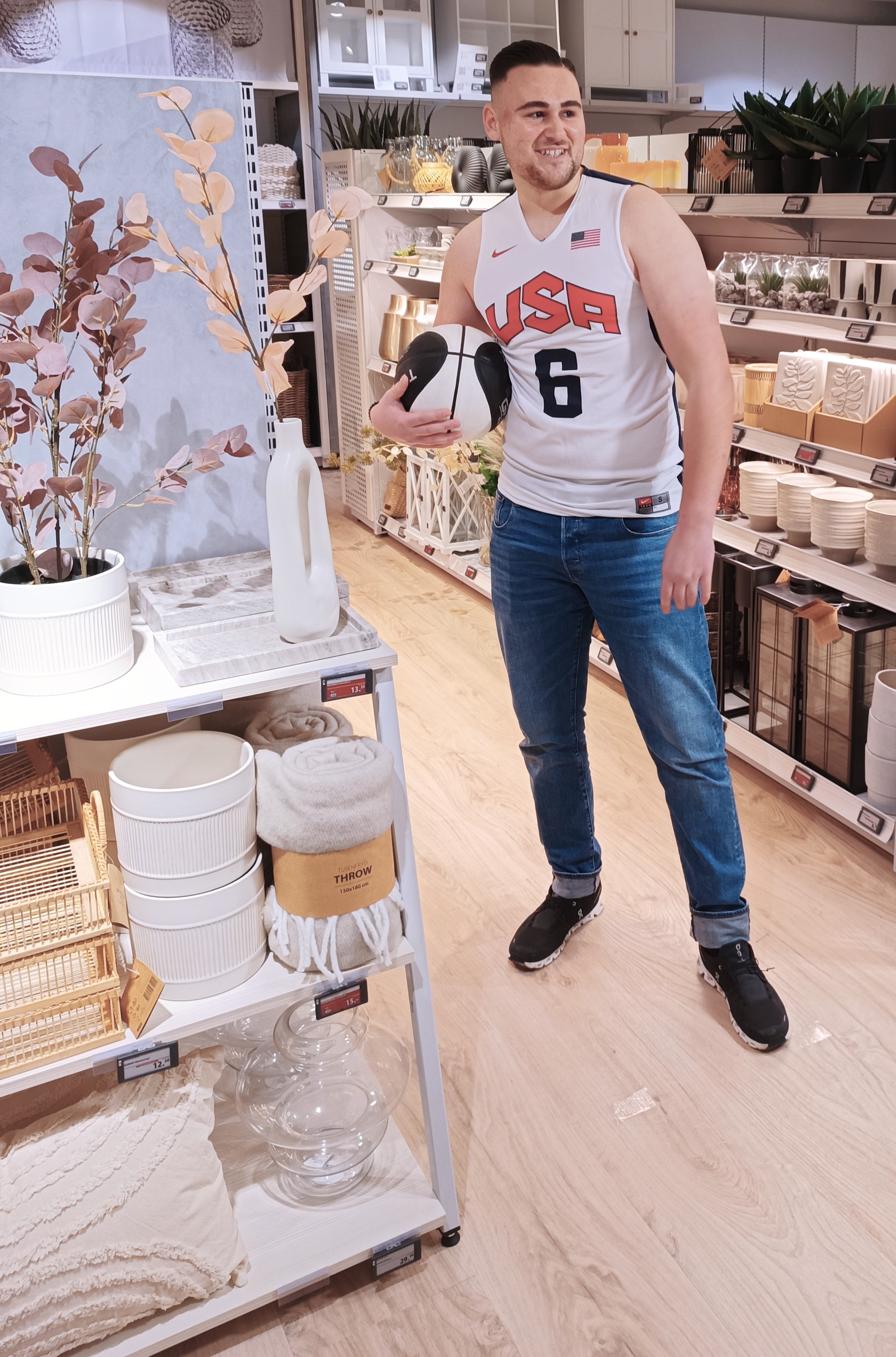 Ein junger, großer Mann mit Basketball in der Hand steht im Store