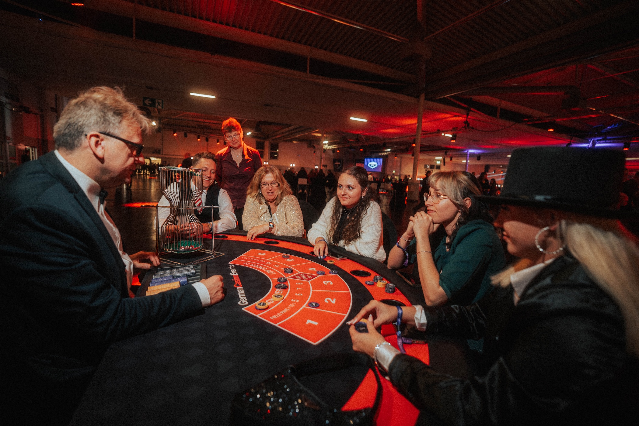 Mehrere Frauen und zwei Männer sitzen an einem Casino-Tisch