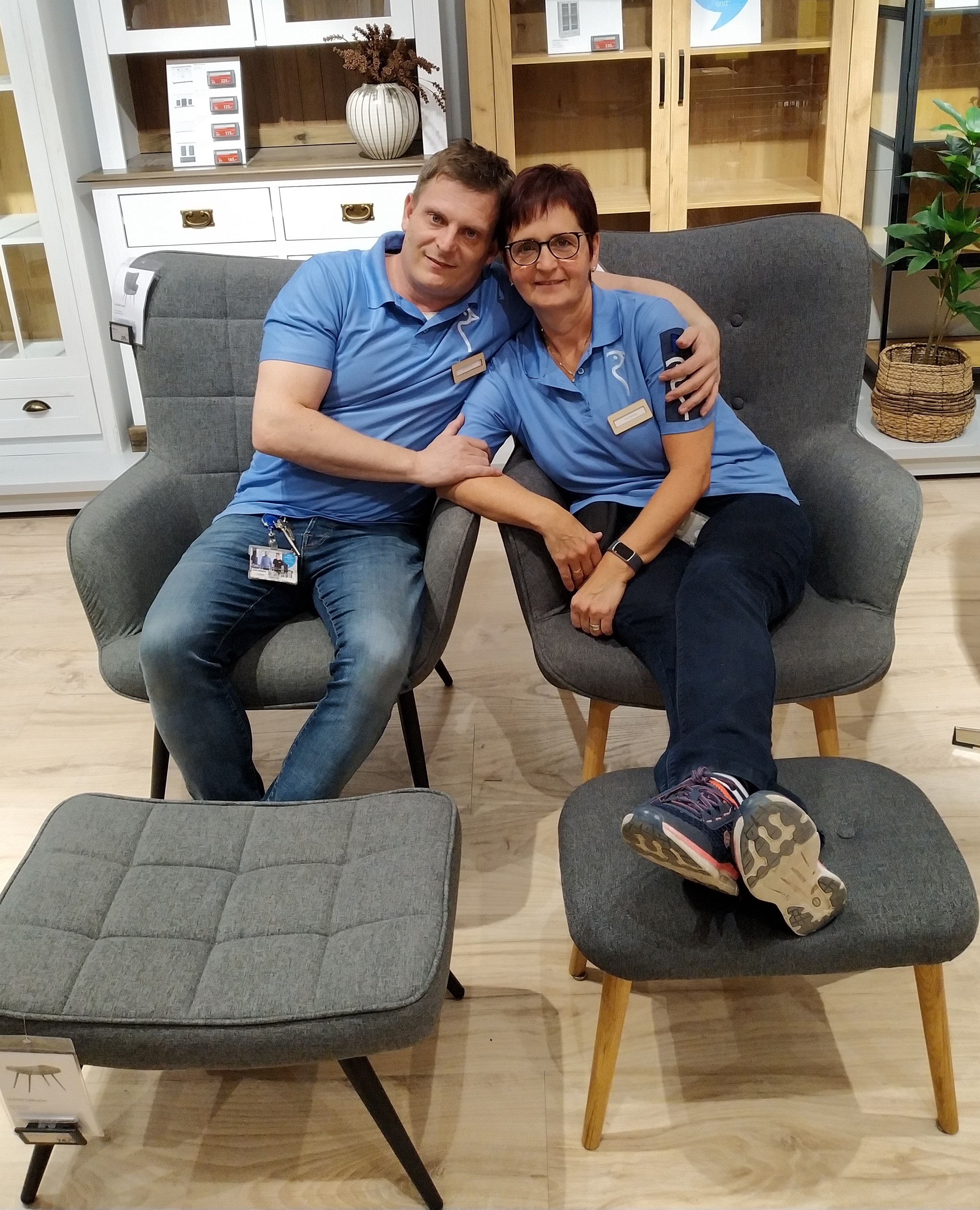 Ein Mann und eine Frau sitzen in zwei Sesseln. Der Mann lehnt sich an die Frau.