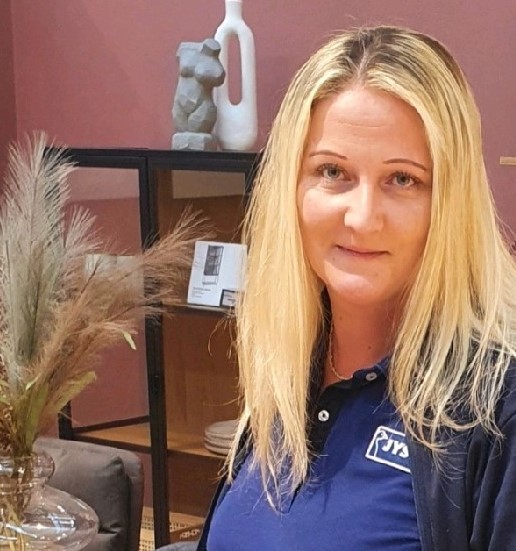 Das Bild zeigt Deputy Store Manager Jacqueline Barth. Sie hat langes Haar und trägt ein JYSK Poloshiert sowie eine Strickjacke. 