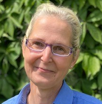 Das Bild zeigt Kerstin. Sie trägt eine Brille, ihre Haare sind nach hinten zu einem Pferdeschwanz gebunden. 