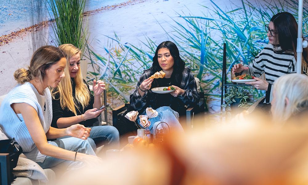En grupp inluencers äter fika i ett svart loungeset.
