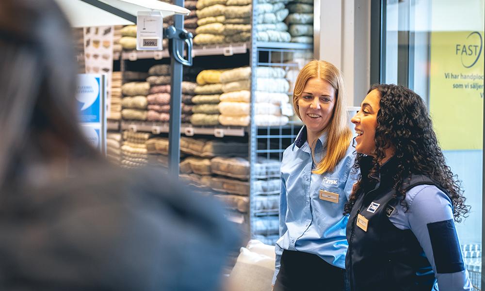 Ronja Ali står och berättar om trädgårdssortimentet. Sandra Martinsson står bredvid och tittar på Ronja. 