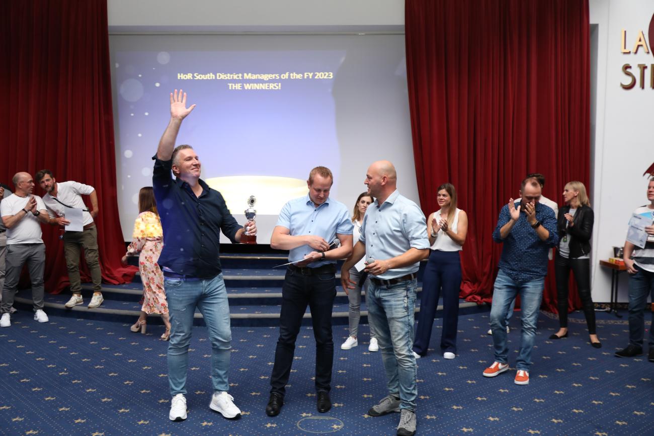 Jan (links) schnappte sich den Titel in Region 9 und ließ sich gebührend feiern, unter anderem von Retail Manager Markus (Mitte) und Head of Retail Tobias (rechts).