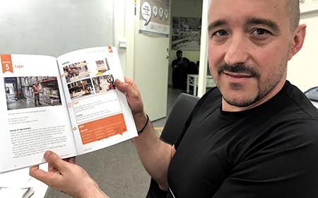 Kostantinos Koutoulakis visar upp läroboken som används i undervisningen för yrkessvenska. 