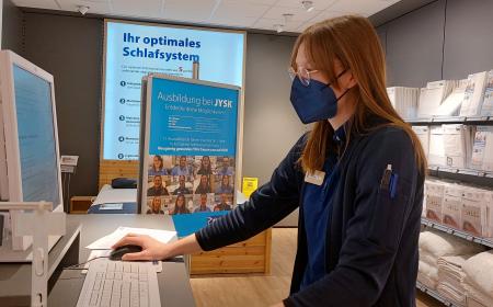 Eine junge Frau steht an einem PC 