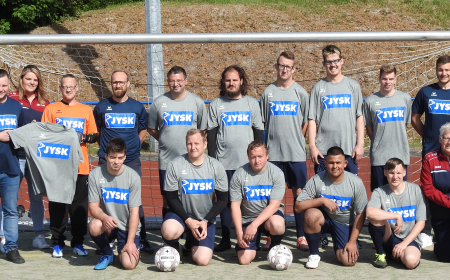 Mehrere Menschen, größtenteils Männer, stehen und hocken vor einem Fußballtor