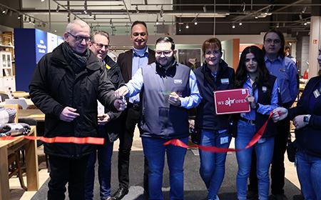 Bürgermeister und Store Manager durchschneiden das Rote Band