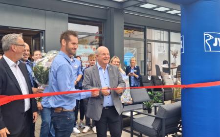 Zwei Männer schneiden mit einer Schere ein Band durch. Im Hintergrund stehen viele Leute und freuen sich 