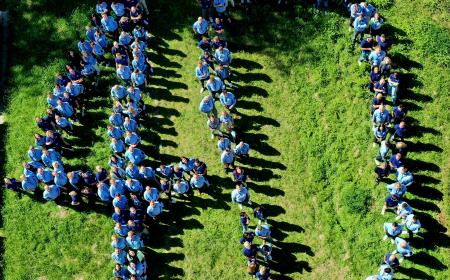 Zahlreiche Menschen in JYSK-Hemden und Poloshirts stehen auf einer wiese. Gemeinsam formen sie eine 40